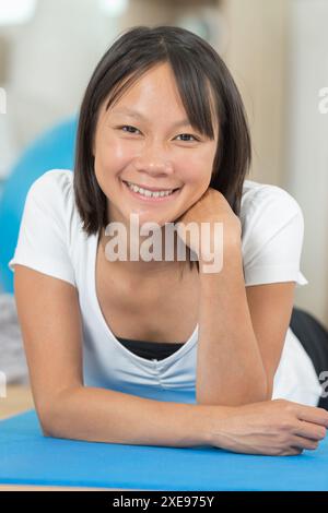 donna sorridente dopo aver fatto delle spaccature sul tappeto a casa Foto Stock