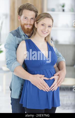 coppia incinta che abbraccia e sorride Foto Stock
