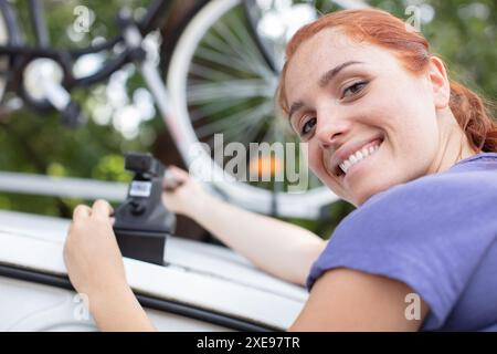 Femmina matura ciclista prendendo in mountain bike dalla cremagliera sulla vettura Foto Stock