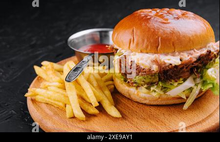 Delizioso hamburger con salsa al formaggio e patatine fritte su un tavolo di legno Foto Stock