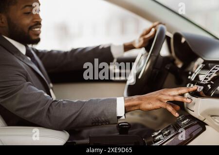 Uomo afroamericano che regola il controllo della climatizzazione all'interno dell'auto Foto Stock