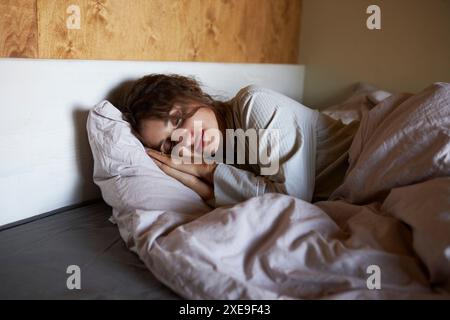 Foto di una giovane donna addormentata giace a letto con gli occhi chiusi Foto Stock