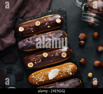 Dolci eclari di cioccolato su tavola di legno nera Foto Stock