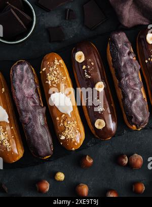 Dolci eclari di cioccolato su tavola di legno nera Foto Stock