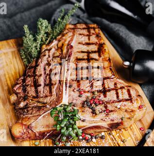 Una grande bistecca alla griglia su un piatto di legno Foto Stock