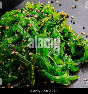 Insalata di alghe wakame con semi di sesamo su piatto nero Foto Stock