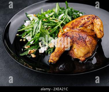 Pollo fritto con insalata di rucola su piatto nero Foto Stock