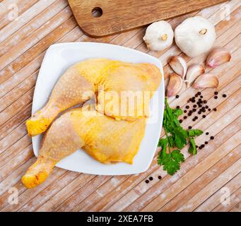 Quarti di coscia di pollo crudo su tavola di legno Foto Stock