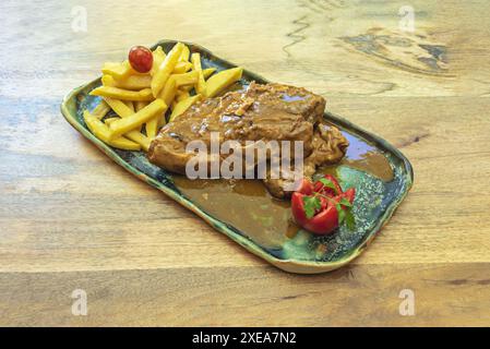 costolette di maiale con patatine fritte, puoi semplicemente tagliare le patate a fette o bastoncini, friggerle in olio caldo fino a quando non diventano dorate e croccanti, e condire con sale e spi Foto Stock