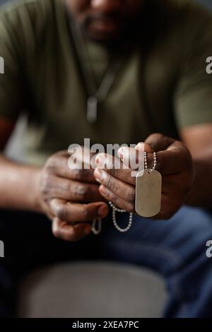 Primo piano verticale di un uomo nero irriconoscibile come veterano dell'esercito che tiene in mano le targhette durante la sessione di terapia Foto Stock