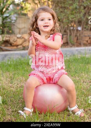 La ragazza si siede su un'enorme palla rosa. Foto Stock