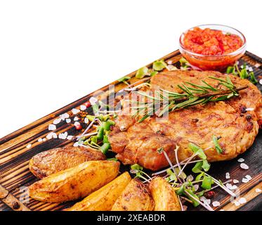 Bistecca alla griglia con patate al forno su legno Foto Stock