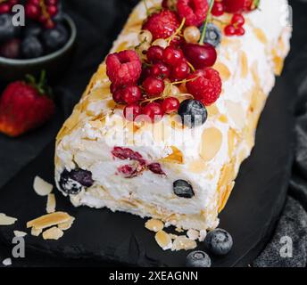 Rotolo di meringa con panna, frutti di bosco e mandorle Foto Stock