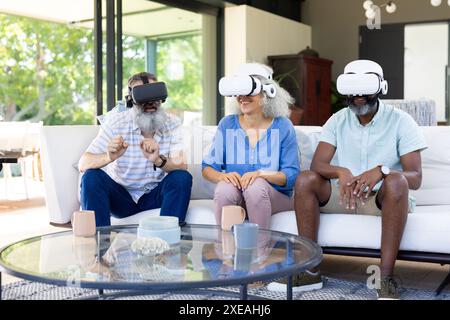 A casa, un gruppo eterogeneo di amici che utilizzano visori VR, godendo di un'esperienza di realtà virtuale Foto Stock