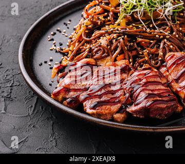 Manzo di soba e verdure, spaghetti di grano saraceno su sfondo di pietra scura Foto Stock