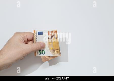 Mano che tiene cinquanta banconote in euro su sfondo bianco Foto Stock