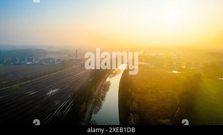 La prima luce dell'alba sul tranquillo canale e sulla ferrovia in campagna Foto Stock