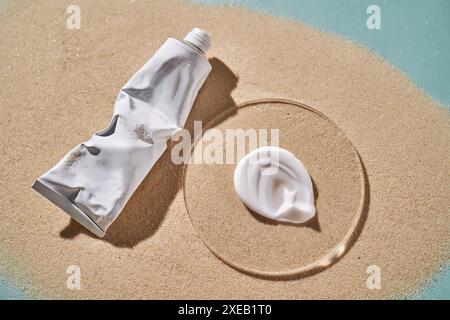 Un tubo di crema solare idratante e uno striscio su fondo sabbioso. Foto Stock