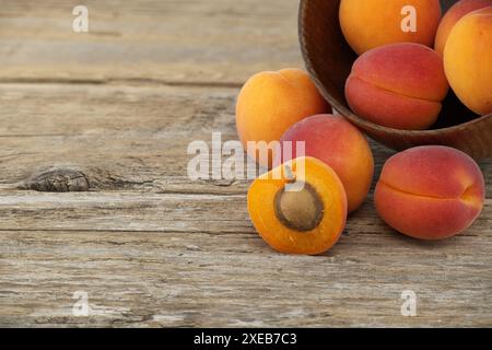 Una pila di albicocche mature e una tagliata a metà per mostrare il suo interno succulento, un tavolo rustico in legno Foto Stock