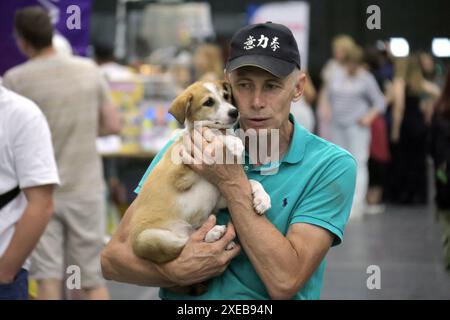 Non esclusivo: KIEV, UCRAINA - 22 GIUGNO 2024 - Un uomo porta un cane durante l'evento del giorno dell'adozione presso il Centro esposizioni Internazionale di Kiev, capitale Foto Stock