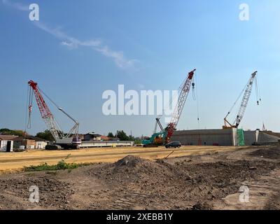 gru cingolata. Gru cingolata gialla elettrica diesel in un grande cantiere, comprese diverse gru che lavorano in un complesso edilizio, Foto Stock