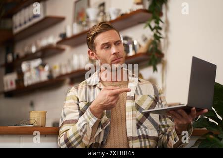 Hai ragione. Ritratto di un uomo serio concorda con il collega, puntare il dito sullo schermo del notebook, connettersi alla videochat, ha truffato Foto Stock