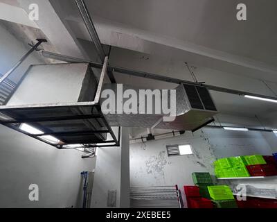 Pulizia dei condotti HVAC, tubi di ventilazione in materiale isolante argentato appeso al soffitto all'interno di un nuovo edificio. Tubi di ventilazione Foto Stock