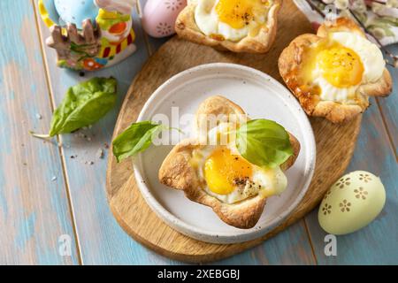 Uova strapazzate in pasta sfoglia con formaggio e pancetta. Colazione di Pasqua su un tavolo festivo. Vista dall'alto. Foto Stock