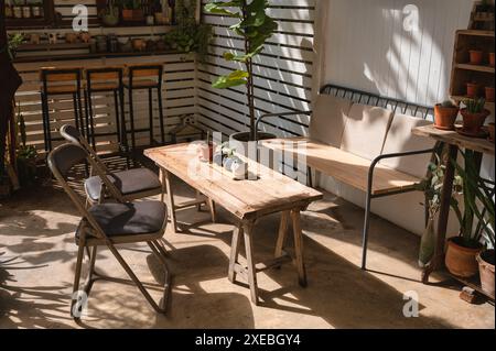 Il design retrò di un caffè all'aperto con tavolo in legno, sedia e vaso di cactus decorato sul cortile Foto Stock
