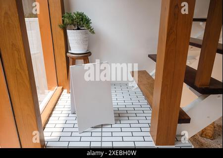 Modella un cartello bianco bianco bianco in piedi con l'impianto in vaso sul pavimento in una casa di legno Foto Stock
