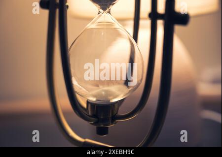 Primo piano del classico vetro vetrato metallico o della clessidra con sabbia bianca che cade giù. il passare del tempo. concetto di scadenza aziendale Foto Stock