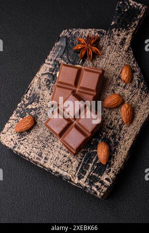 Delizioso cioccolato al latte dolce spezzato a cubetti su un tagliere di legno Foto Stock