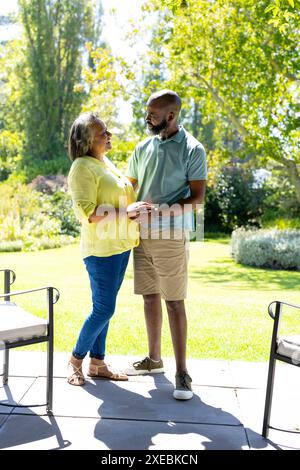 Coppia senior che si tiene per mano e si sorride l'un l'altro in un giardino soleggiato Foto Stock