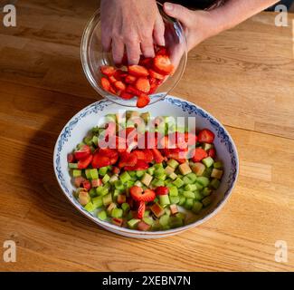 Donna che versa pezzi di fragole in forma di torta Foto Stock