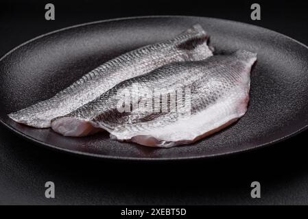 Filetto di pesce di spigola crudo con sale, spezie ed erbe aromatiche su un piatto di ceramica Foto Stock