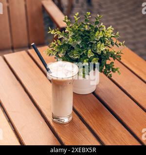 Rinfrescante caffè ghiacciato seduto su un tavolo di legno su una terrazza all'aperto Foto Stock