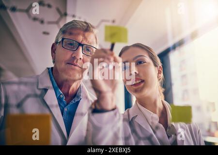 Scienziati, appunti e ricerca con soluzioni, scrittura e innovazione per esperimenti o collaborazione in laboratorio. Uomo, donna e parete di vetro con Foto Stock