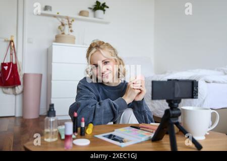 Ritratto di una bella donna bionda, la ragazza mostra blues, prodotti di bellezza, registrazione di video su una fotocamera digitale, creazione di contenuti per Foto Stock