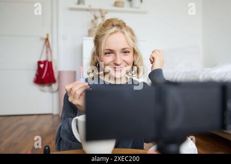 Immagine di un giovane influencer di social media felice e bello, vlogger femminile registra un video su una fotocamera digitale, tutorial su come utilizzare l'unità di elaborazione Foto Stock