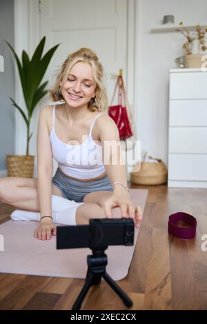 Ripresa verticale di una donna atletica e fitness che registra video di se stessa su una fotocamera digitale, creando contenuti per i social media su W Foto Stock