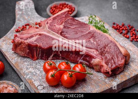 Bistecca di manzo succosa cruda con sale, spezie ed erbe aromatiche Foto Stock