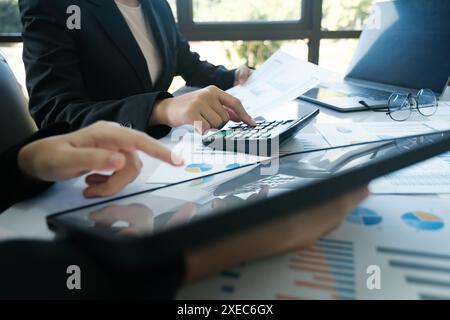 Due persone stanno lavorando su un foglio di calcolo con una calcolatrice Foto Stock