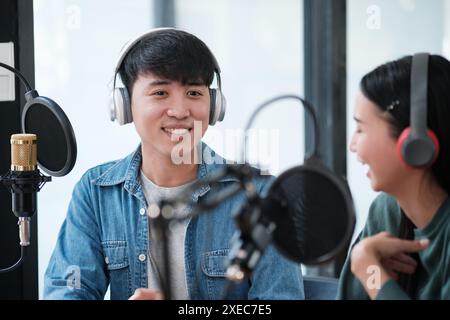 Due persone sono sedute in uno studio con microfoni e cuffie accese Foto Stock