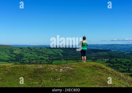 Un viaggiatore solitario si affaccia sulla campagna gallese durante una sosta in auto. Guarda le distese di lussureggianti campagne verdi Foto Stock
