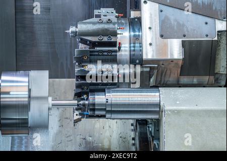 La macchina per tornio CNC che forma il taglio delle parti metalliche. Lavorazione di metalli ad alta tecnologia mediante tornitura CNC . Foto Stock