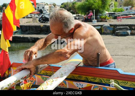ACI TREZZA, ITALIA - 24 GIUGNO 2024 - Festa tradizionale di San Giovanni. Sfilata tradizionale di San Giovanni con pisci a mari dove riproducono la caccia al tonno. Il tonno viene derubato da un giovane che finalmente riesce a fuggire dai pescatori Foto Stock