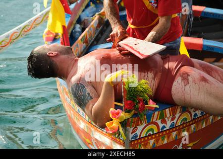 ACI TREZZA, ITALIA - 24 GIUGNO 2024 - Festa tradizionale di San Giovanni. Sfilata tradizionale di San Giovanni con pisci a mari dove riproducono la caccia al tonno. Il tonno viene derubato da un giovane che finalmente riesce a fuggire dai pescatori Foto Stock