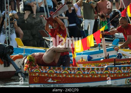 ACI TREZZA, ITALIA - 24 GIUGNO 2024 - Festa tradizionale di San Giovanni. Sfilata tradizionale di San Giovanni con pisci a mari dove riproducono la caccia al tonno. Il tonno viene derubato da un giovane che finalmente riesce a fuggire dai pescatori Foto Stock