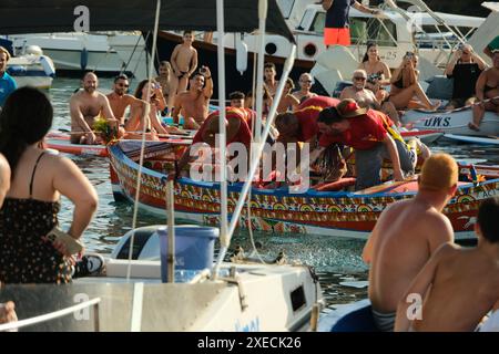 ACI TREZZA, ITALIA - 24 GIUGNO 2024 - Festa tradizionale di San Giovanni. Sfilata tradizionale di San Giovanni con pisci a mari dove riproducono la caccia al tonno. Il tonno viene derubato da un giovane che finalmente riesce a fuggire dai pescatori Foto Stock