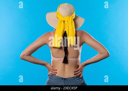 Una donna con un grande cappello da spiaggia tiene le mani sui fianchi. Foto Stock